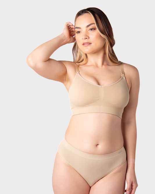 Woman wearing a beige nursing bra and underwear set on a light grey background