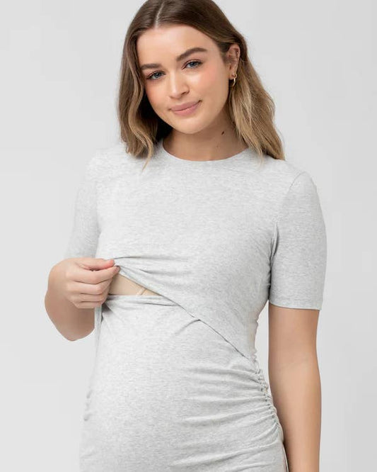 Pregnant Woman wearing a grey nursing maternity dress with a white background