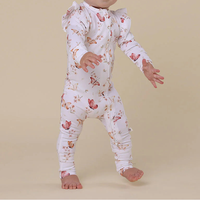 Baby wearing a floral onesie on a beige background