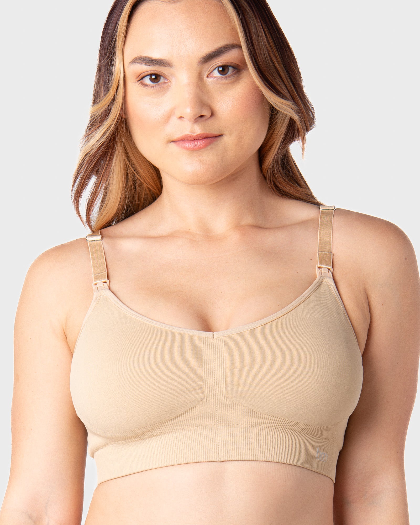 Woman wearing a beige nursing bra against a plain background