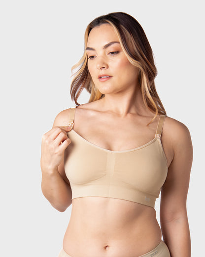 Woman wearing a beige nursing bra against a white background