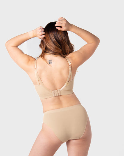 Woman wearing beige nursing bra on a plain background