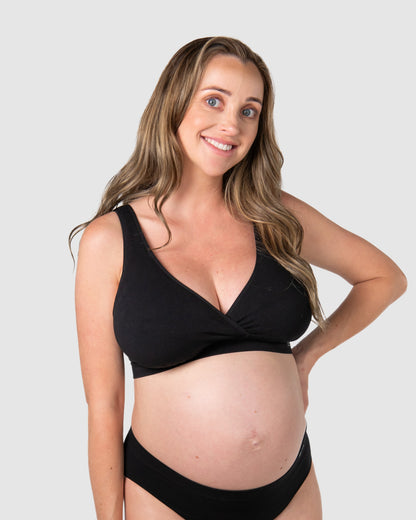 Pregnant woman wearing a black maternity bikini set on a plain background