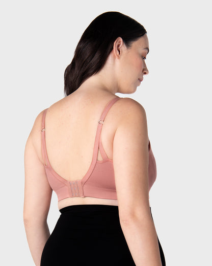 Pregnant Woman wearing a pink nursing bra against a plain background