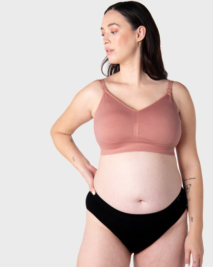 Pregnant Woman wearing a brown nursing bra and black underwear on a white background