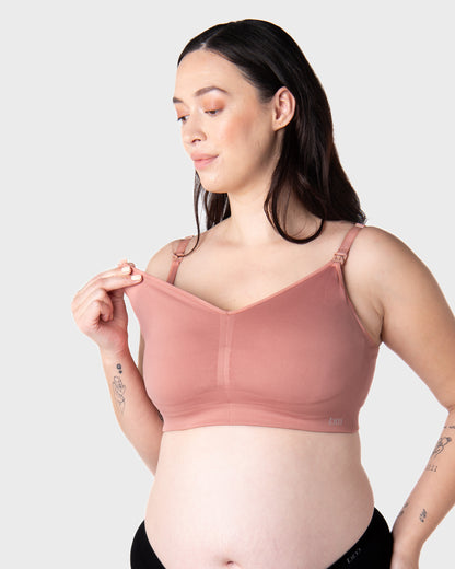 Pregnant Woman wearing a pink nursing bra against a plain background
