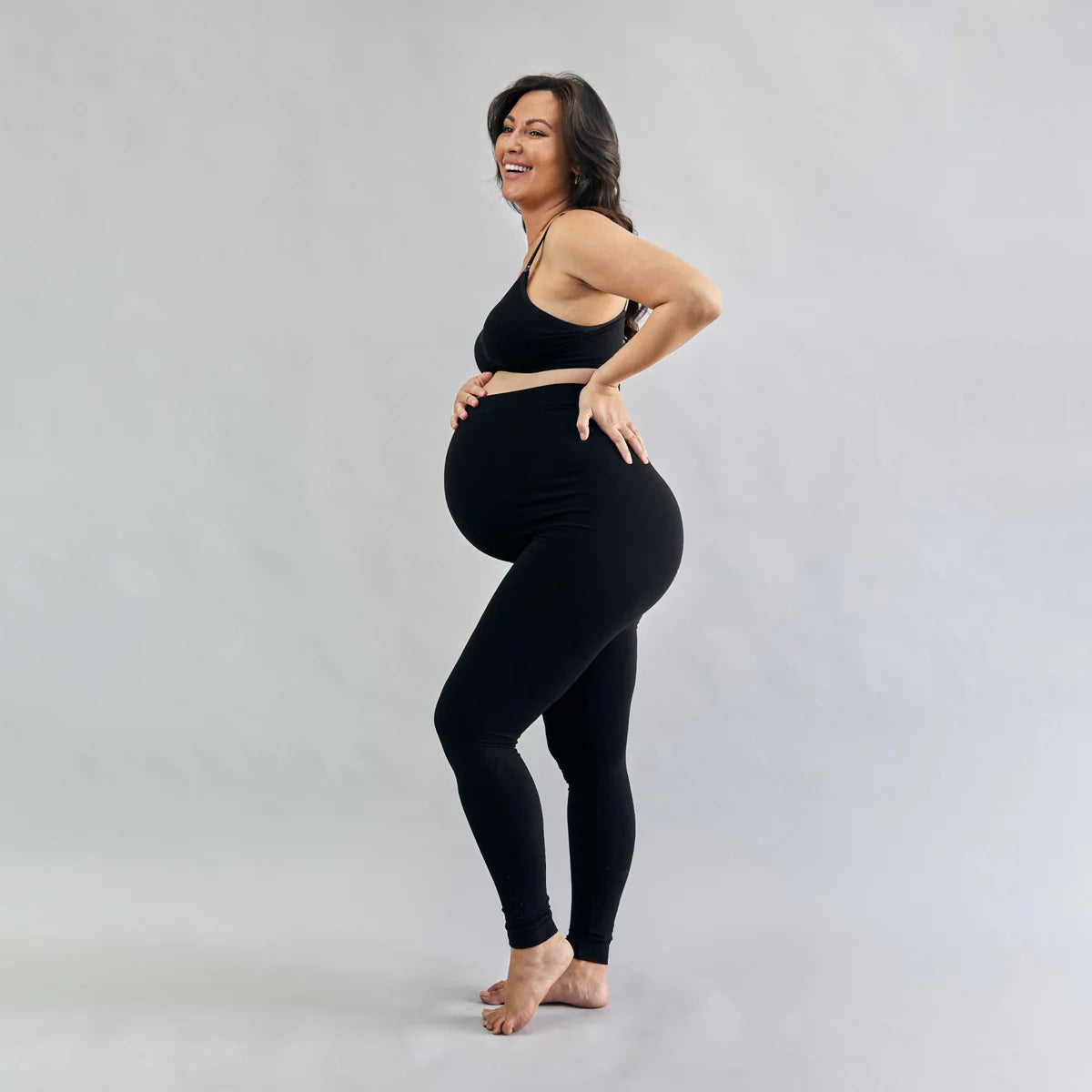 Pregnant woman wearing a black outfit on a plain background
