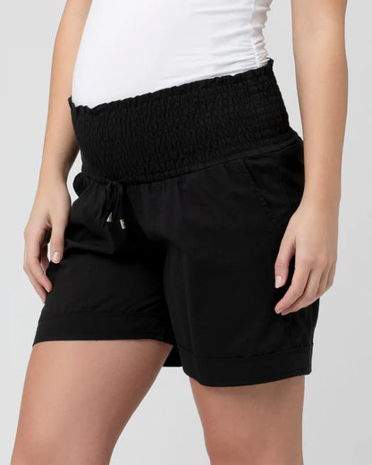 Black  maternity shorts with a white top on a plain background