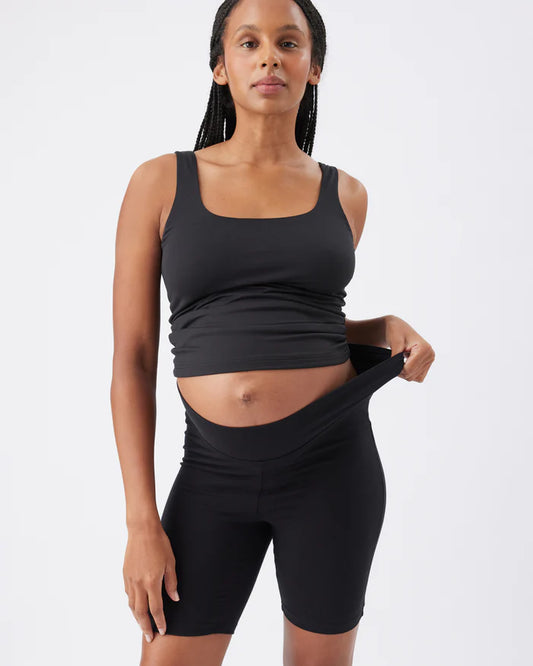 Pregnant Woman wearing a black athletic maternity outfit on a white background