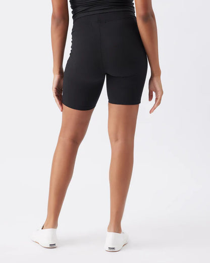 Pregnant woman wearing black maternity biker shorts on a white background