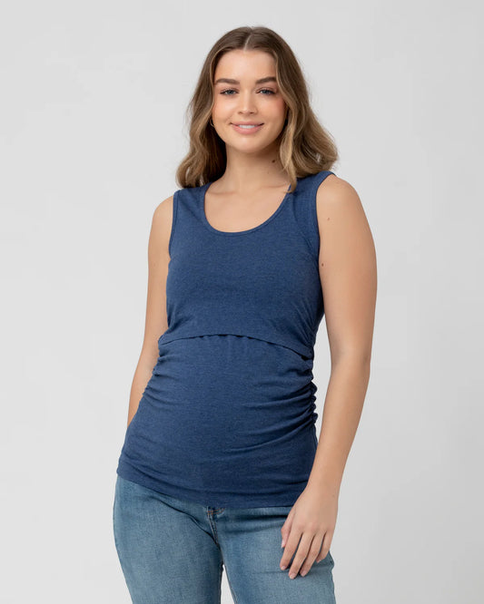Pregnant Woman wearing a blue nursing tank top and jeans on a plain background