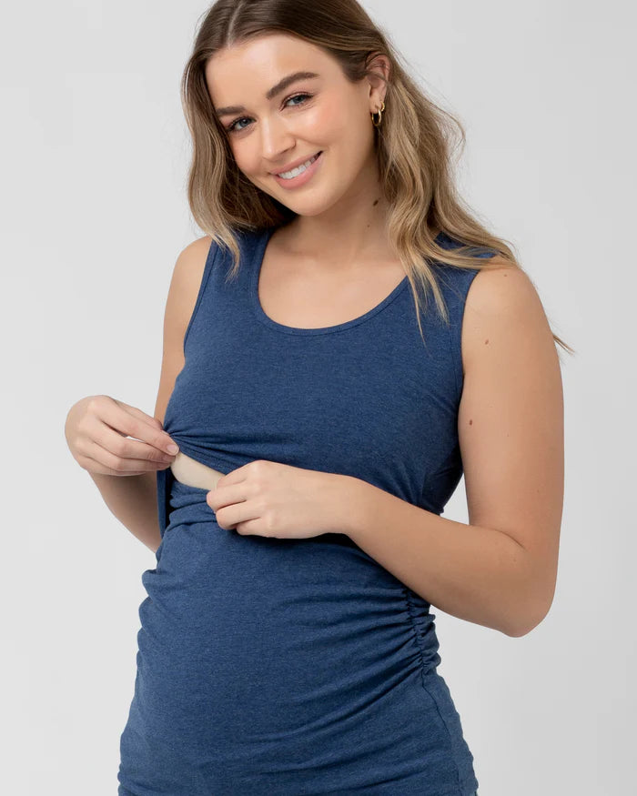 Pregnant Woman wearing a blue sleeveless nursing tank against a plain background