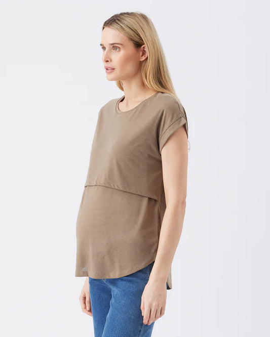 Pregnant Woman wearing an olive maternity top and blue jeans on a white background