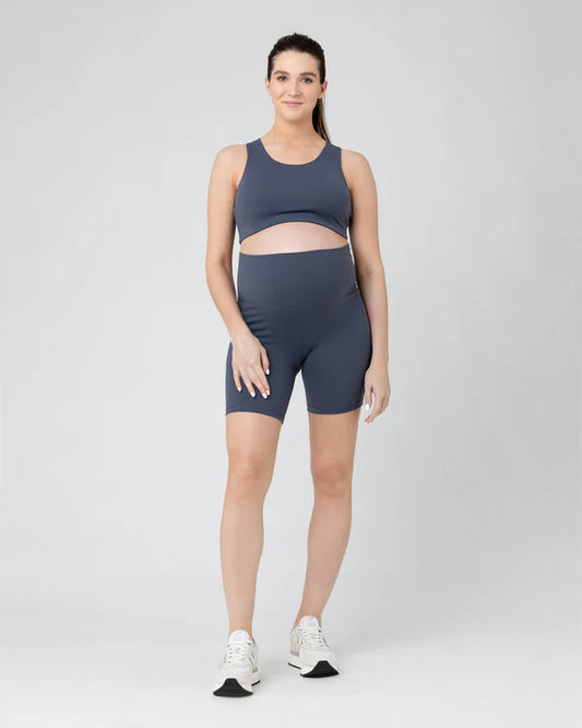 Pregnant Woman wearing a blue maternity athletic outfit on a white background
