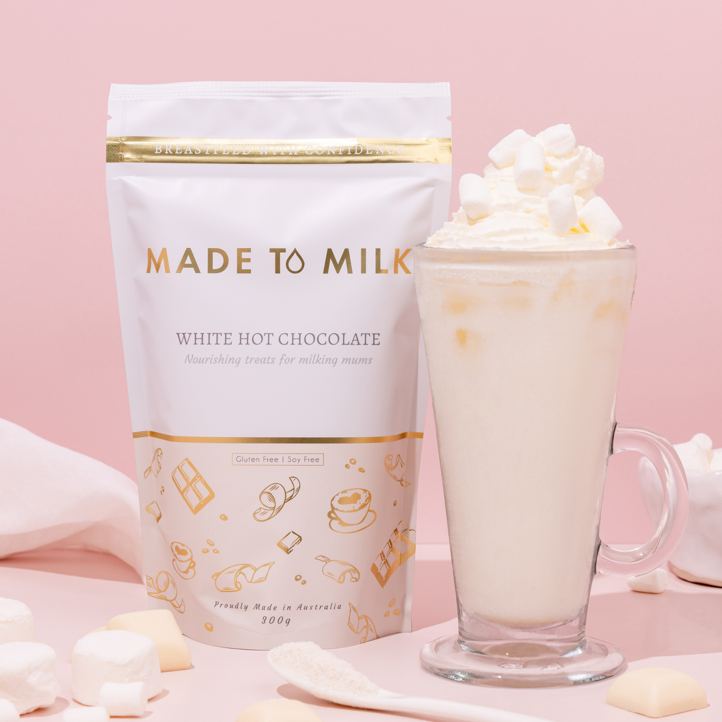 Made to Milk white hot chocolate package with a glass of hot chocolate on a pink background