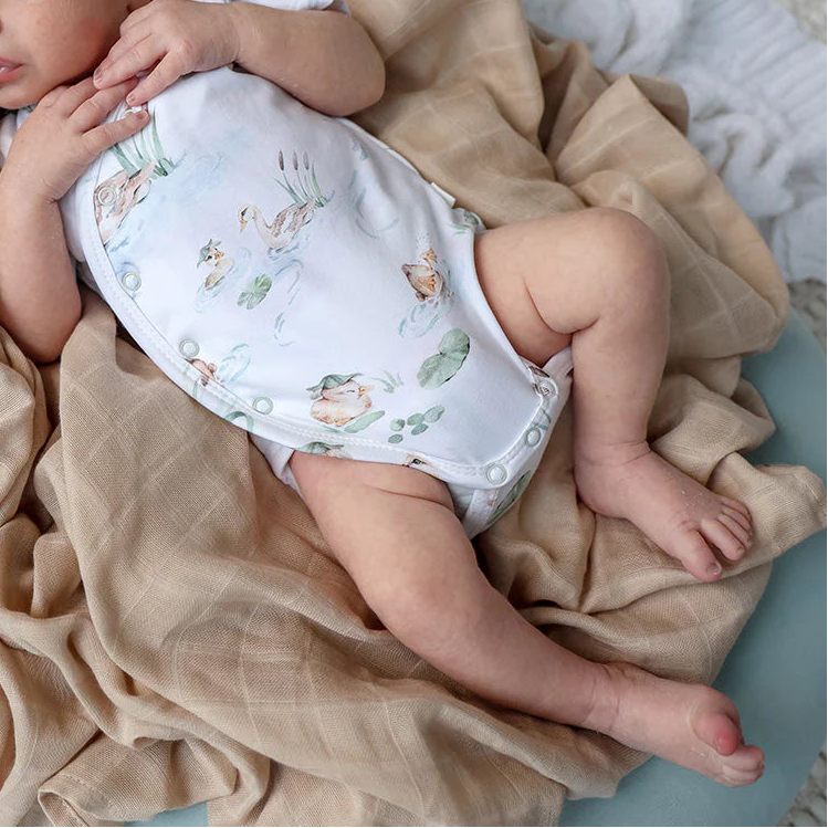Newborn baby sleeping in a crib with beige bedding