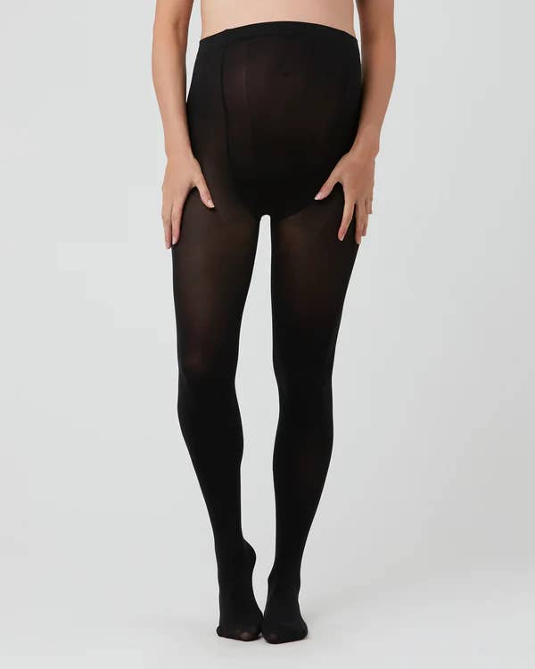 Pregnant woman wearing black tights on a plain background