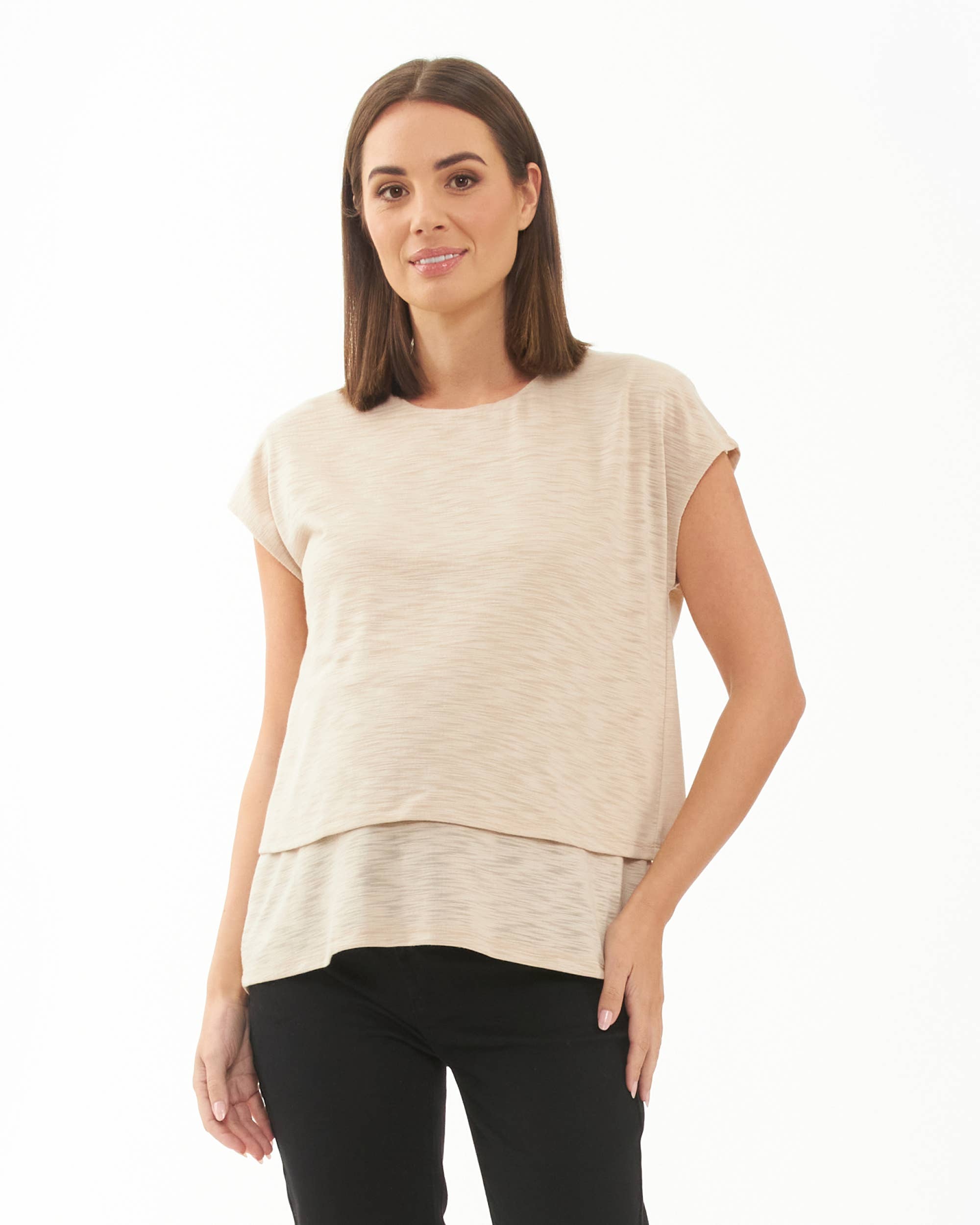 Pregnant Woman wearing a beige top and black pants on a white background