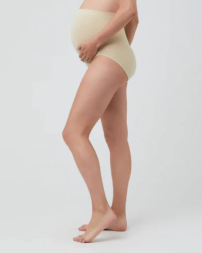 Person wearing beige maternity pants on a plain background