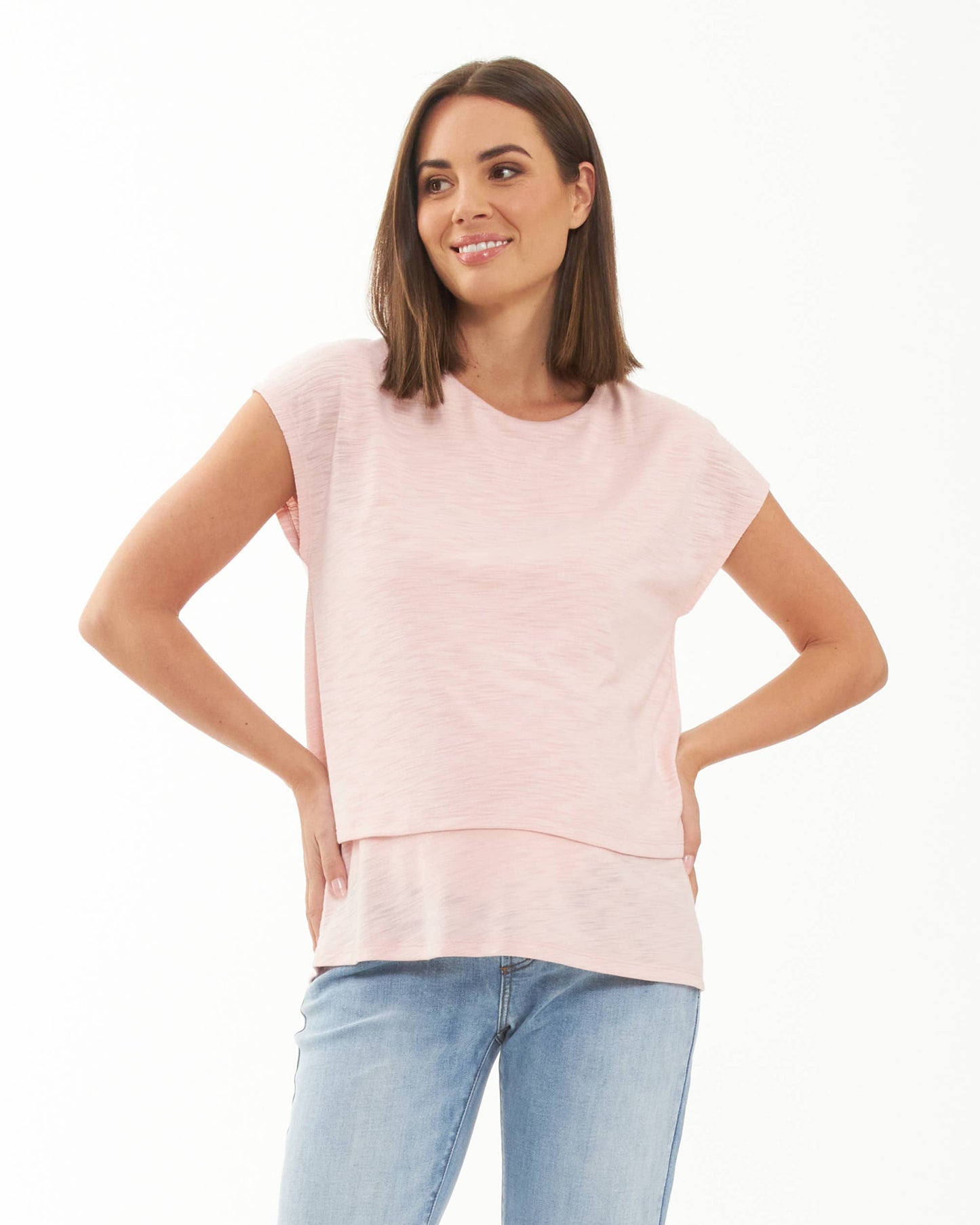Pregnant Woman wearing a light pink top and blue jeans on a white background