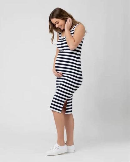 Pregnant woman wearing a black and white striped dress on a plain background