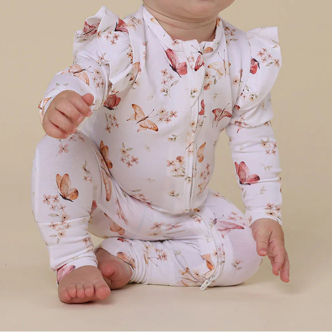 Baby wearing a floral onesie sitting on a beige background