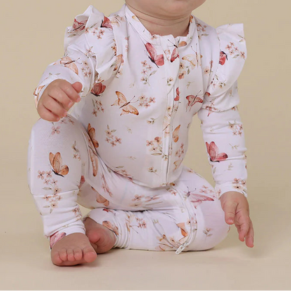 Baby wearing a floral onesie sitting on a beige background